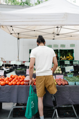 Man with a prosthetic leg standing in front of Fruit Stand